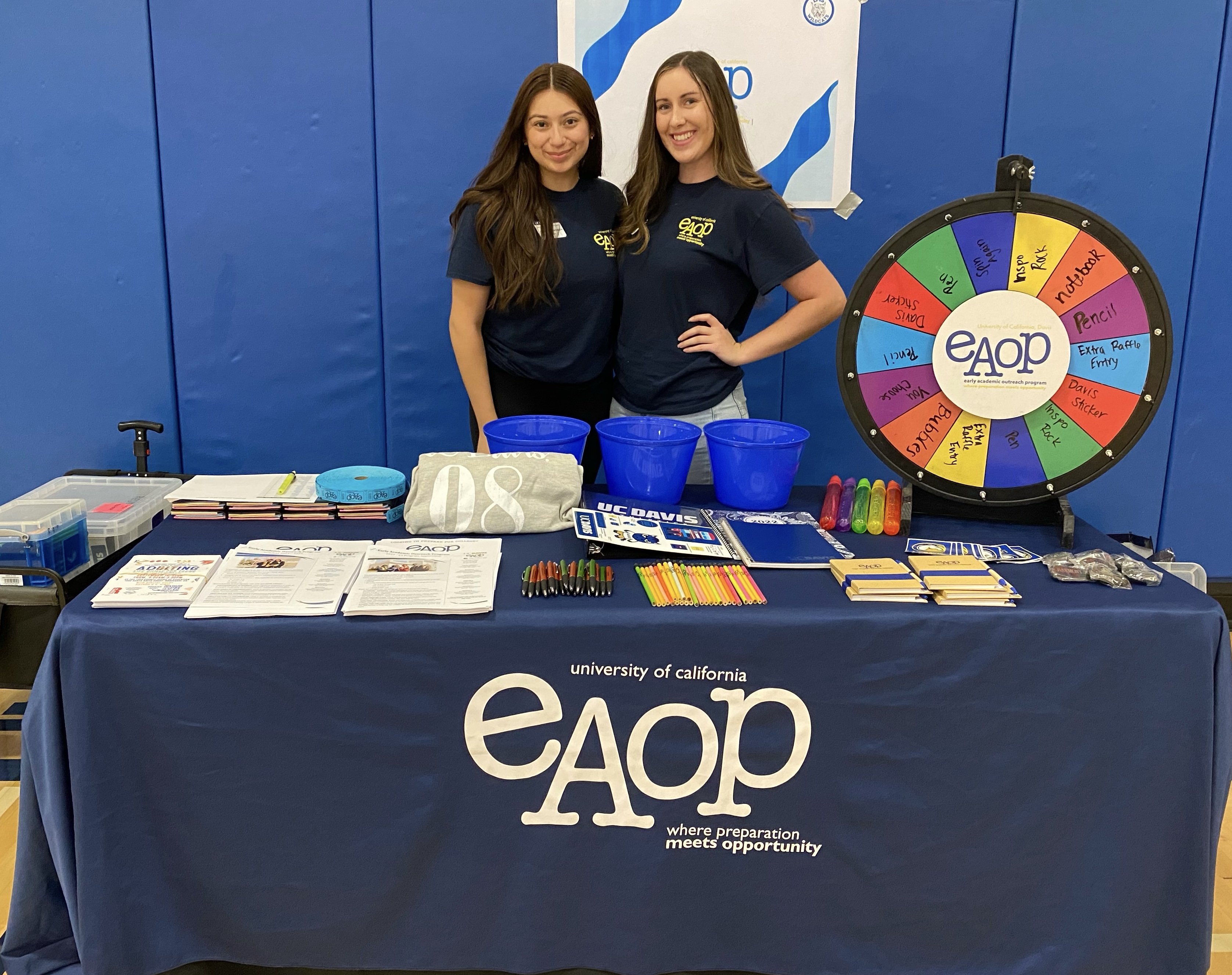 Two individuals smiling behind an EAOP recruitment table