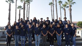 Group picture of current EAOP staff standing in front of palm trees. 